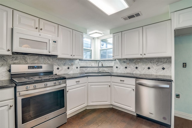 kitchen with appliances with stainless steel finishes, sink, dark wood-type flooring, white cabinets, and decorative backsplash