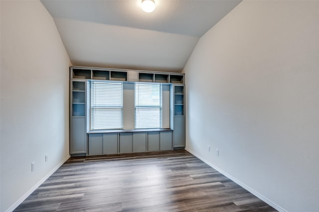 spare room featuring baseboards, vaulted ceiling, and wood finished floors