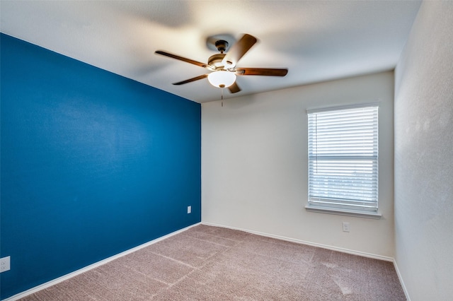 carpeted empty room with ceiling fan and baseboards