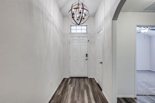 doorway to outside with baseboards, visible vents, arched walkways, dark wood-style floors, and an inviting chandelier