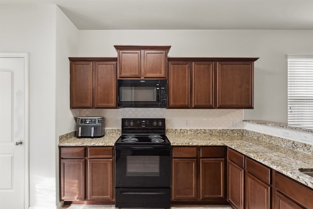 kitchen featuring tasteful backsplash, light stone countertops, and black appliances