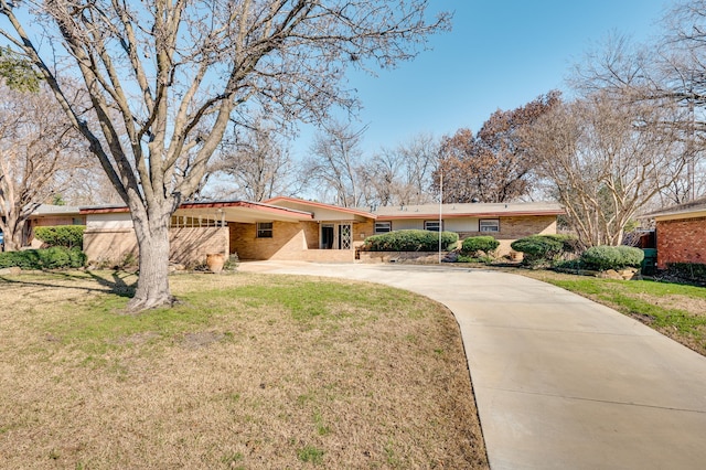 ranch-style house with concrete driveway, a front lawn, and brick siding