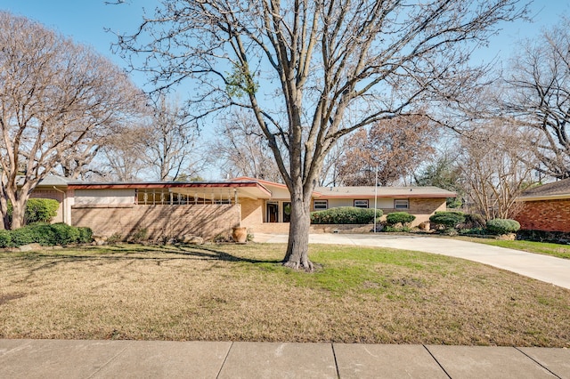 view of front of home with concrete driveway, brick siding, and a front yard