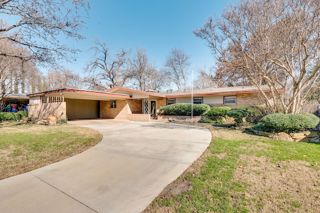 view of front of property with brick siding, an attached carport, concrete driveway, and a front yard