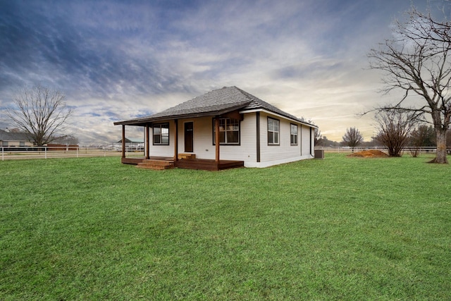 rear view of house with a porch, a yard, and fence