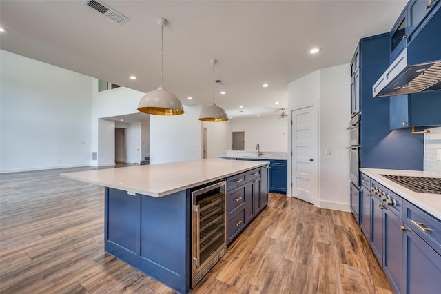 kitchen featuring blue cabinetry, pendant lighting, light countertops, and open floor plan