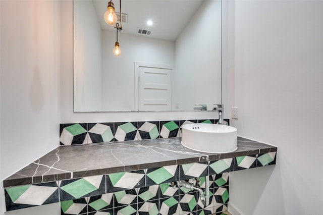 bathroom with tasteful backsplash, a sink, and visible vents