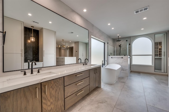 bathroom featuring a stall shower, a freestanding tub, visible vents, and a sink