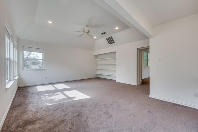 carpeted empty room with lofted ceiling, a ceiling fan, baseboards, visible vents, and built in features