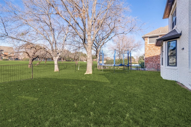 view of yard with a trampoline and fence