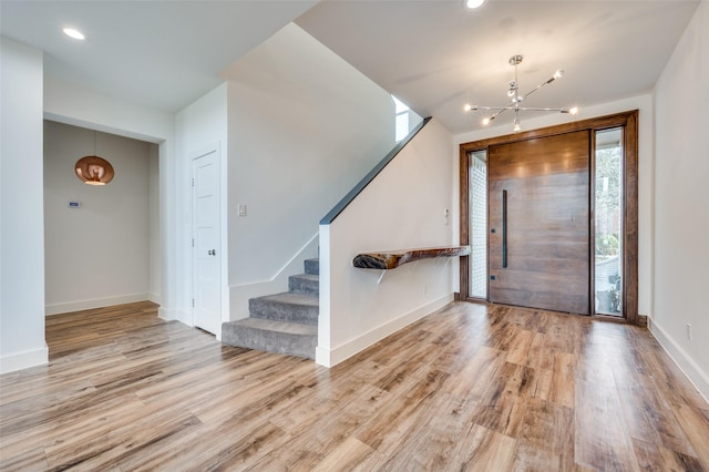 entryway featuring light wood finished floors, plenty of natural light, stairs, and baseboards