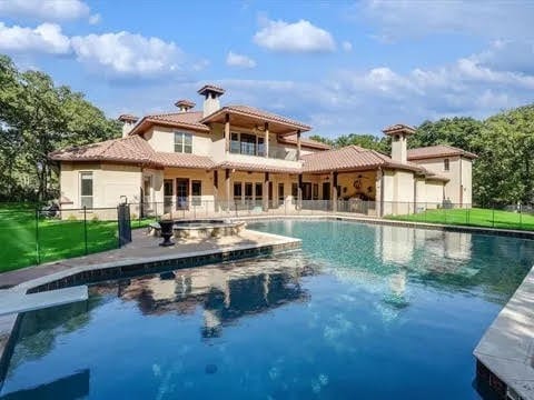 back of house with fence, an outdoor pool, and a tiled roof