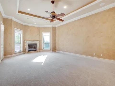 unfurnished living room featuring a tray ceiling, light colored carpet, and crown molding