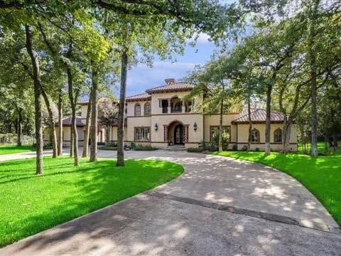 mediterranean / spanish house with driveway, stucco siding, a front lawn, and a tiled roof