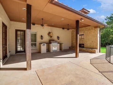 view of patio / terrace with an outdoor brick fireplace, exterior kitchen, and a ceiling fan