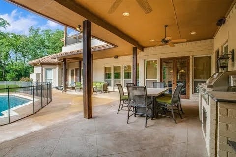 view of patio / terrace featuring exterior kitchen, a fenced in pool, and a ceiling fan