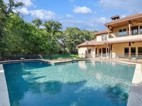 pool with an in ground hot tub, a patio, and fence