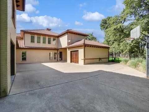 view of front facade featuring a tiled roof, a patio area, and stucco siding