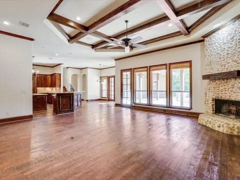 unfurnished living room with dark wood-style flooring, coffered ceiling, and a stone fireplace