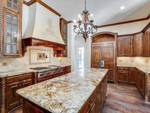 kitchen featuring ornamental molding, a center island, hanging light fixtures, custom exhaust hood, and stainless steel gas stovetop