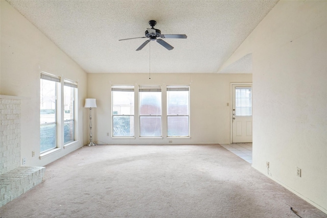 spare room with a textured ceiling, vaulted ceiling, light colored carpet, and ceiling fan