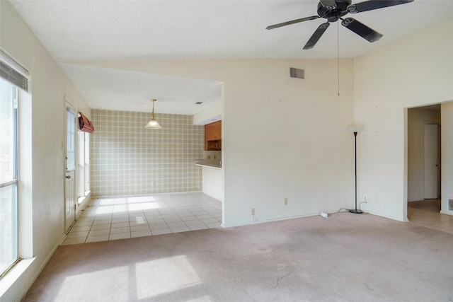 carpeted empty room featuring vaulted ceiling, ceiling fan, and tile walls