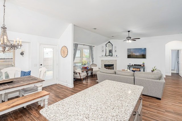 living room featuring ceiling fan with notable chandelier, vaulted ceiling, and dark hardwood / wood-style flooring