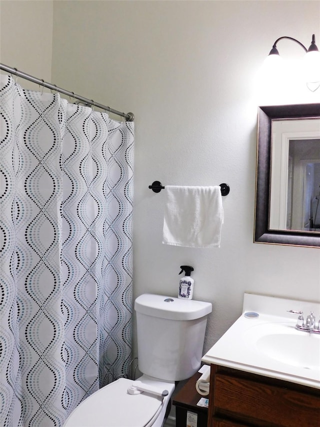 bathroom featuring toilet, vanity, and walk in shower