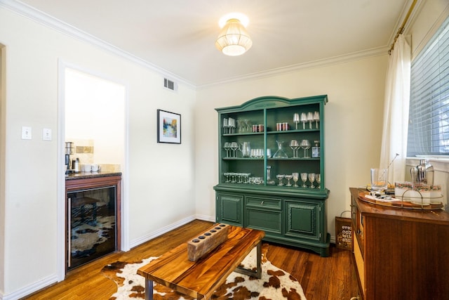 bar with dark wood-style floors, ornamental molding, and visible vents