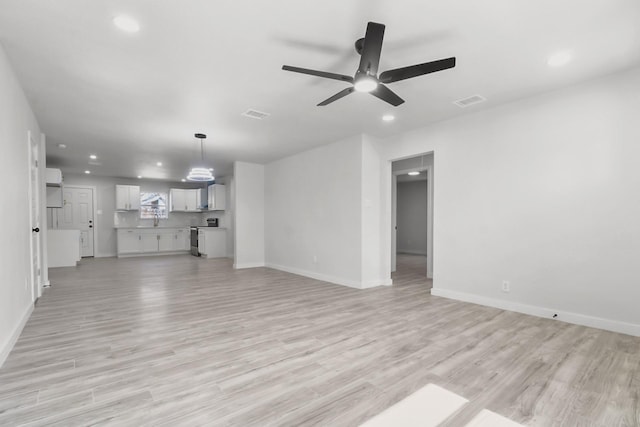 unfurnished living room with ceiling fan, light hardwood / wood-style flooring, and sink