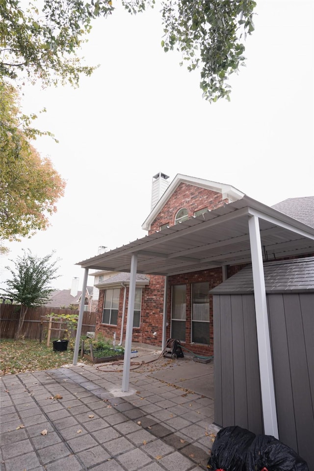 view of patio / terrace with a storage unit and fence