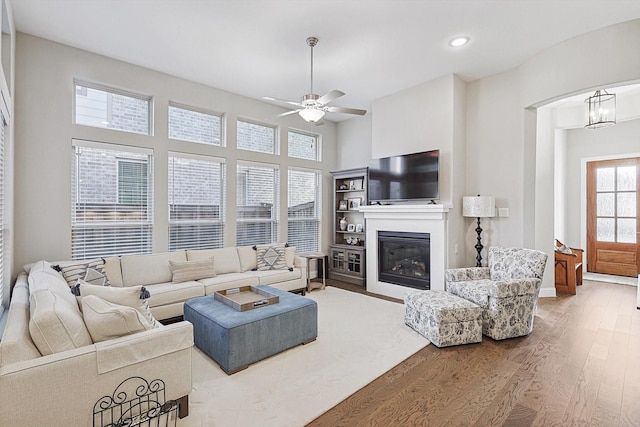 living room with ceiling fan with notable chandelier and hardwood / wood-style floors