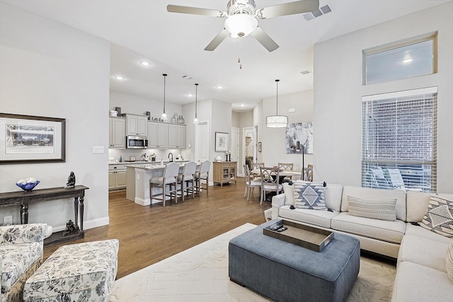 living room with light wood-type flooring and ceiling fan