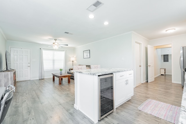 kitchen featuring visible vents, beverage cooler, light wood-style floors, light stone countertops, and white cabinets