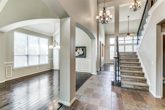 entrance foyer with ceiling fan with notable chandelier and a high ceiling