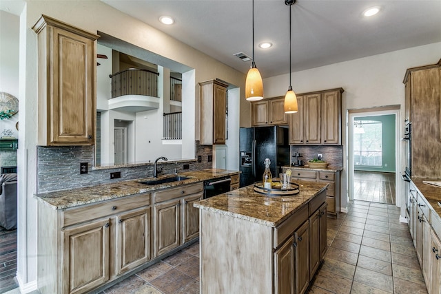 kitchen with light stone counters, a kitchen island, pendant lighting, and black appliances