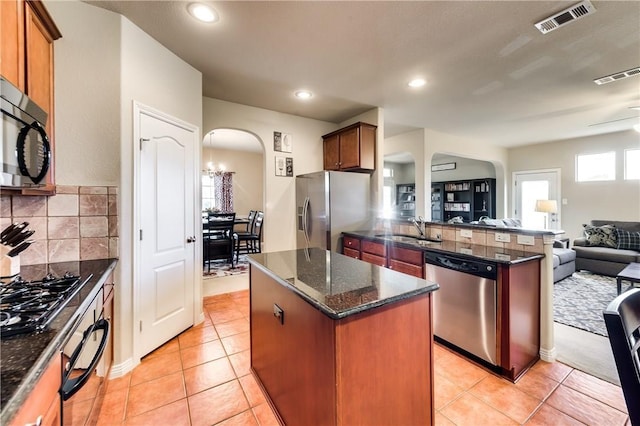 kitchen featuring dark stone countertops, sink, backsplash, a kitchen island, and stainless steel appliances