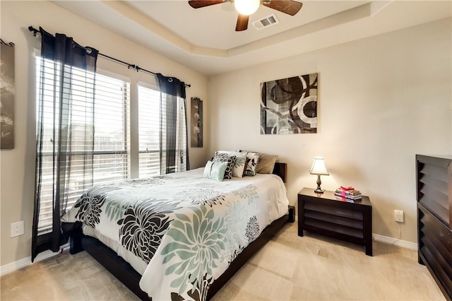 carpeted bedroom with a raised ceiling and ceiling fan