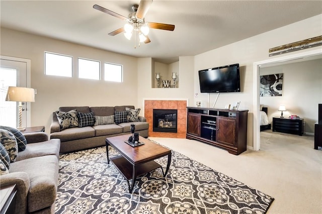 living room featuring ceiling fan, light carpet, and a tiled fireplace