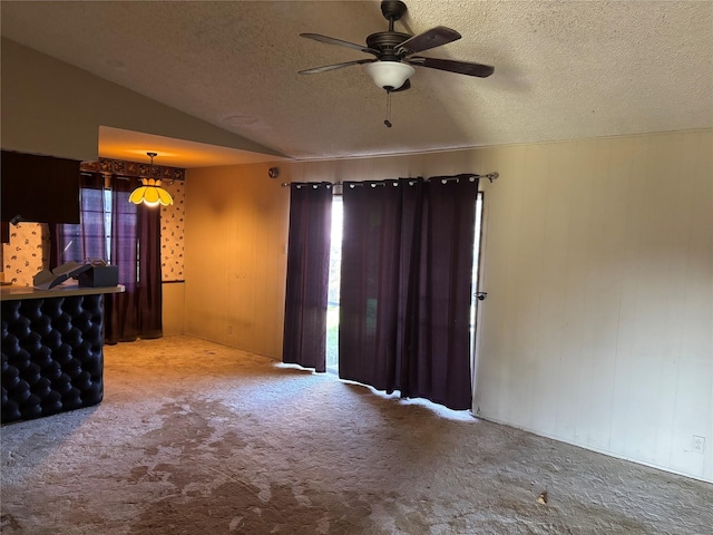 carpeted spare room with a textured ceiling, lofted ceiling, and ceiling fan