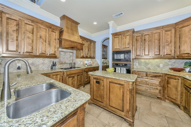 kitchen featuring a center island, sink, light stone countertops, and black appliances