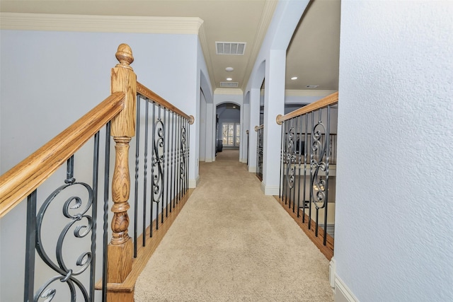 hall with ornamental molding and light colored carpet