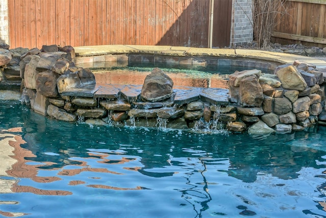 view of swimming pool with a small pond