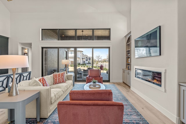 living room with light hardwood / wood-style floors and a towering ceiling