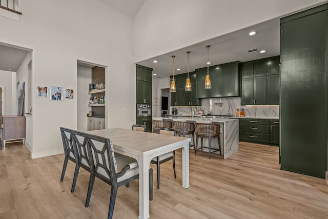 dining space featuring sink, a towering ceiling, and light hardwood / wood-style floors