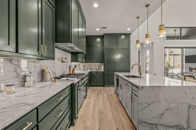 kitchen featuring hanging light fixtures, appliances with stainless steel finishes, sink, and green cabinetry