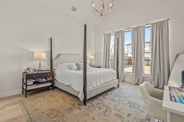 bedroom with an inviting chandelier, lofted ceiling, and light hardwood / wood-style flooring