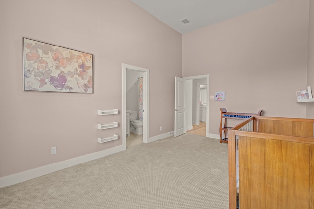 carpeted bedroom with ensuite bath and a high ceiling