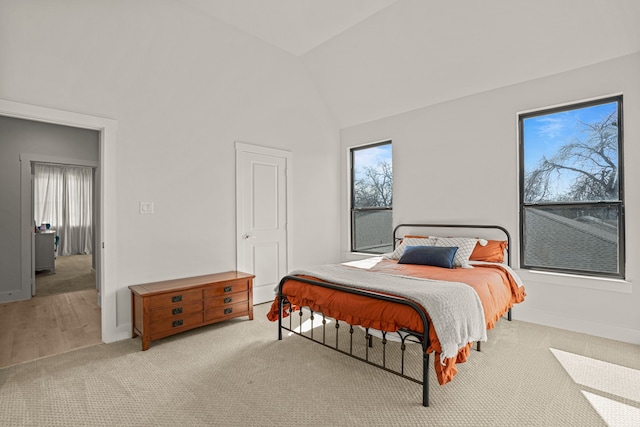 bedroom featuring high vaulted ceiling and light colored carpet