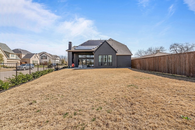 back of house with a yard, solar panels, and a patio area